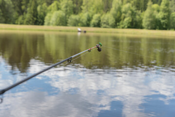 A fishing float bell at the tip of a rod, gently swaying on a calm lake at dawn, capturing the...