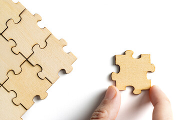 hand holding wooden jigsaw puzzle pieces. To complete the puzzle. business and teamwork concept.