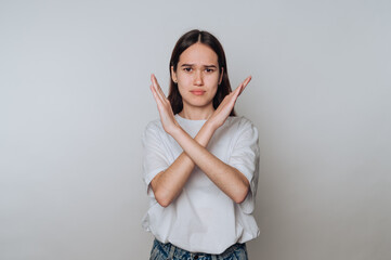 Young asian woman making a gesture of refusal with crossed arms on a plain background