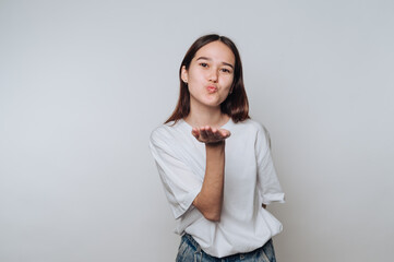 Young woman blowing a kiss against a plain background in a relaxed indoor setting