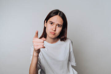Young woman expresses disapproval while pointing fingers in a light studio setting