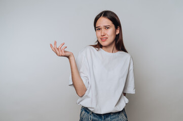 Young asian woman expressing confusion while standing against a plain background in a casual outfit...