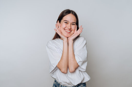 Young aisan woman smiling with hands on her cheeks in a studio setting during daylight hours