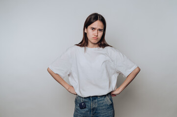 Young woman expressing disappointment while standing against a plain background in casual attire