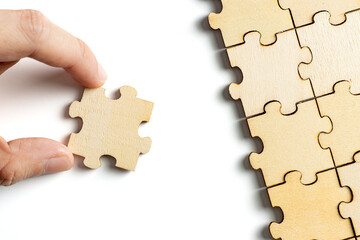 hand holding wooden jigsaw puzzle pieces. To complete the puzzle. business and teamwork concept.
