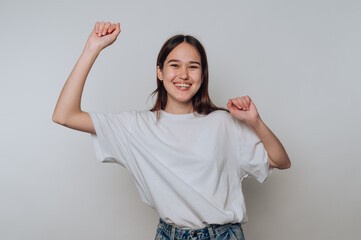 Young asian woman dances joyfully indoors during daytime in casual clothing with a bright, cheerful...