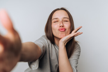 Young woman playfully takes selfie with a cheerful expression in a bright indoor setting
