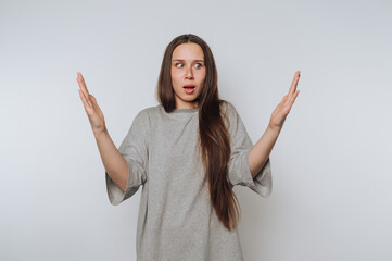 Young woman expressing surprise and confusion with outstretched arms against a light background