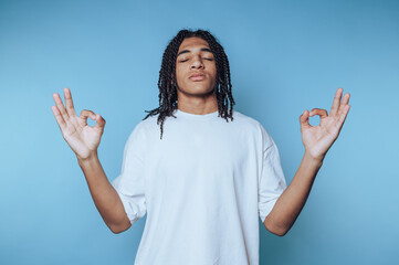 Young person practicing mindfulness and meditation against a calm blue background in a relaxed pose