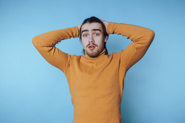 Young man expressing surprise in front of a light blue background during a casual moment