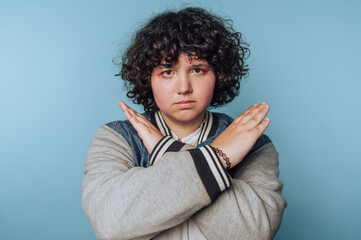 Young person showing a defiant gesture against a blue background in an expressive pose