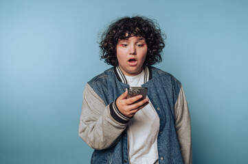 Surprised individual reacting to unexpected news while checking phone against a blue background