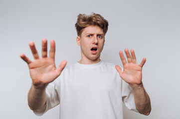 Man with surprised expression raises hands in a gesture of surprise against a white background