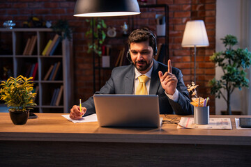 Indian businessman writes notes during online call, showing focus, learning, and remote teamwork
