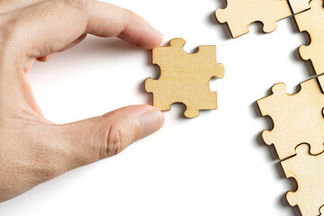 hand holding wooden jigsaw puzzle pieces. To complete the puzzle. business and teamwork concept.