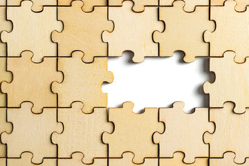 wooden jigsaw puzzle with missing pieces exposing empty white background for copy space.