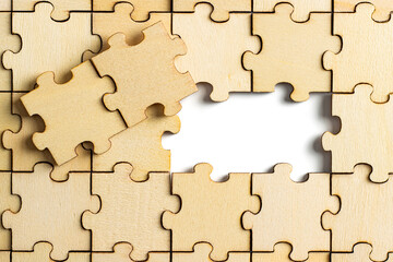 wooden jigsaw puzzle with missing pieces exposing empty white background for copy space.
