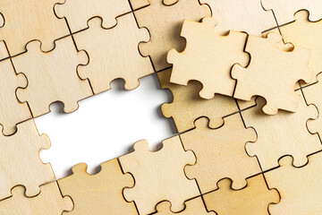wooden jigsaw puzzle with missing pieces exposing empty white background for copy space.