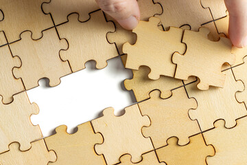 hand holding wooden jigsaw puzzle pieces. To complete the puzzle. business and teamwork concept.