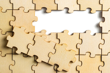 wooden jigsaw puzzle with missing pieces exposing empty white background for copy space.