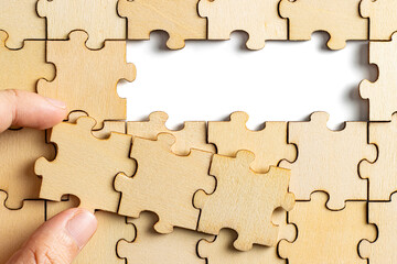 hand holding wooden jigsaw puzzle pieces. To complete the puzzle. business and teamwork concept.