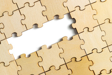 wooden jigsaw puzzle with missing pieces exposing empty white background for copy space.