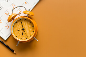 Alarm clock is on calendar with pencil, top view. Planning and time management concept