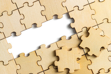 wooden jigsaw puzzle with missing pieces exposing empty white background for copy space.