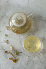 Brewed linden tea in teapot and cup on white background