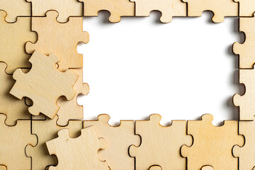 wooden jigsaw puzzle with missing pieces exposing empty white background for copy space.