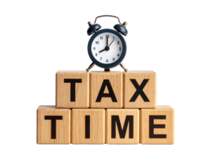 Wooden blocks spelling "TAX TIME" with a small black alarm clock showing 12:00 positioned on top.