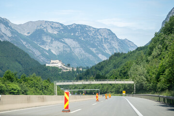 Mountain highway with castle in distance and road construction signs