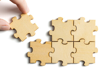 hand holding wooden jigsaw puzzle pieces. To complete the puzzle. business and teamwork concept.