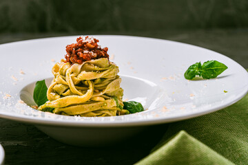 Italian cuisine. Fituccini al pesto on a white plate with a green napkin and cutlery with basil,...