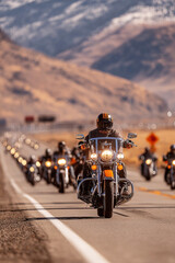 Bikers ride in a large group along a scenic highway on a hot day in the USA