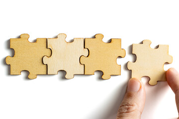hand holding wooden jigsaw puzzle pieces. To complete the puzzle. business and teamwork concept.