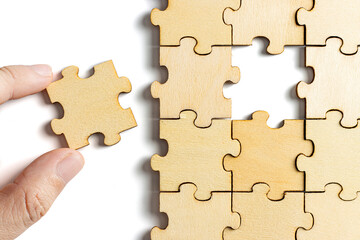 hand holding wooden jigsaw puzzle pieces. To complete the puzzle. business and teamwork concept.