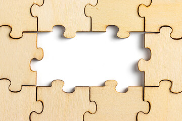 wooden jigsaw puzzle with missing pieces exposing empty white background for copy space.