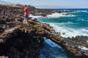 Woman on lava arch above sea