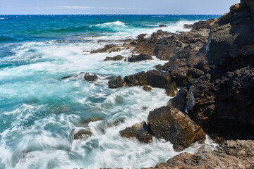 Waves hitting volcanic shoreline
