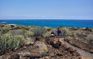 Hiker photographing coast from volcanic trail