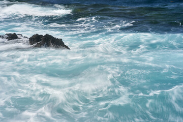 Waves hitting volcanic shoreline