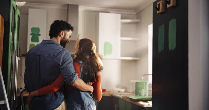 Couple, planning and hug with painting for kitchen renovations, upgrade and maintenance. New home, man and woman back for diy, makeover and decoration decision with creative homeowner and art tools