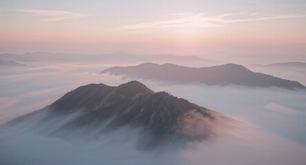 Aerial view of mountain peaks emerging from a sea of fog under a pastel colored sky at dawn or dusk