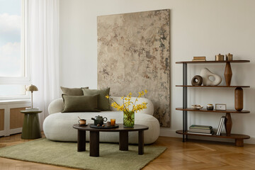 Minimalist living room with green-toned art, sculptural lamp, cozy white sofa, and a round coffee...