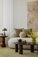 Cozy interior with white boucle sofa, wooden coffee table and artistic wall decor in an earthy...