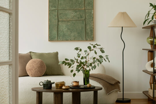 Bright and cozy space with white sofa, modern shelving, spring floral arrangement and sculptural ceramics in a nature-inspired setting.