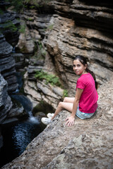 Young hiker sitting on a cliff enjoying the view of a canyon