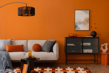 Contemporary interior with orange tones, a black sideboard and a grey sofa adorned with textured...