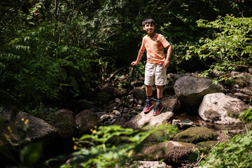 Young hiker exploring forest creek on sunny day